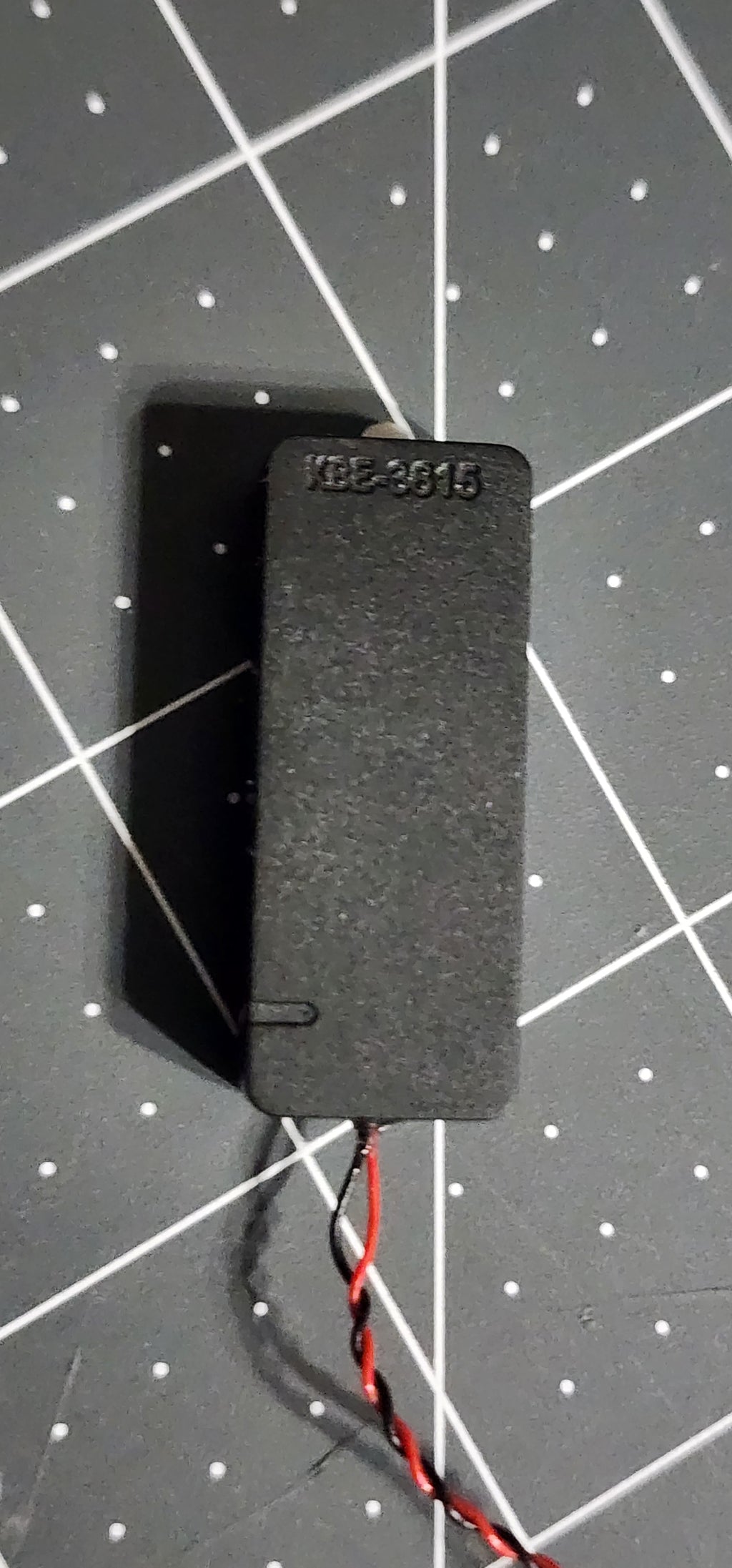 Back of the sealed speaker enclosure with molded KBE-3615 marking and twisted red and black leads