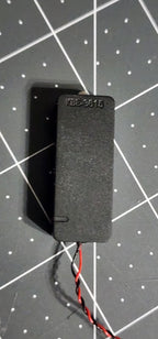 Back of the sealed speaker enclosure with molded KBE-3615 marking and twisted red and black leads