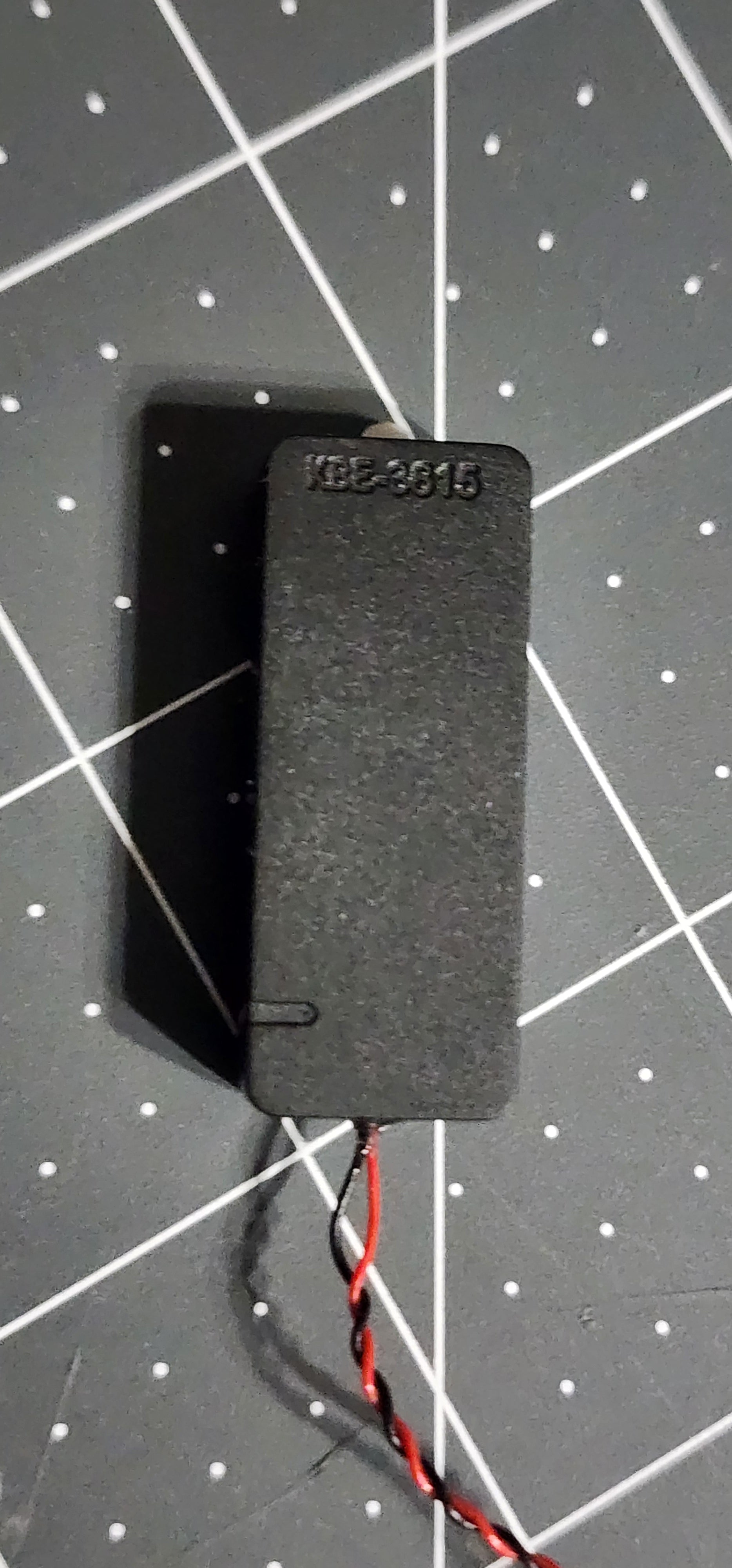 Back of the sealed speaker enclosure with molded KBE-3615 marking and twisted red and black leads