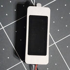 Front of the 36 x 15 mm micro box speaker with stainless frame and sealed black diaphragm window