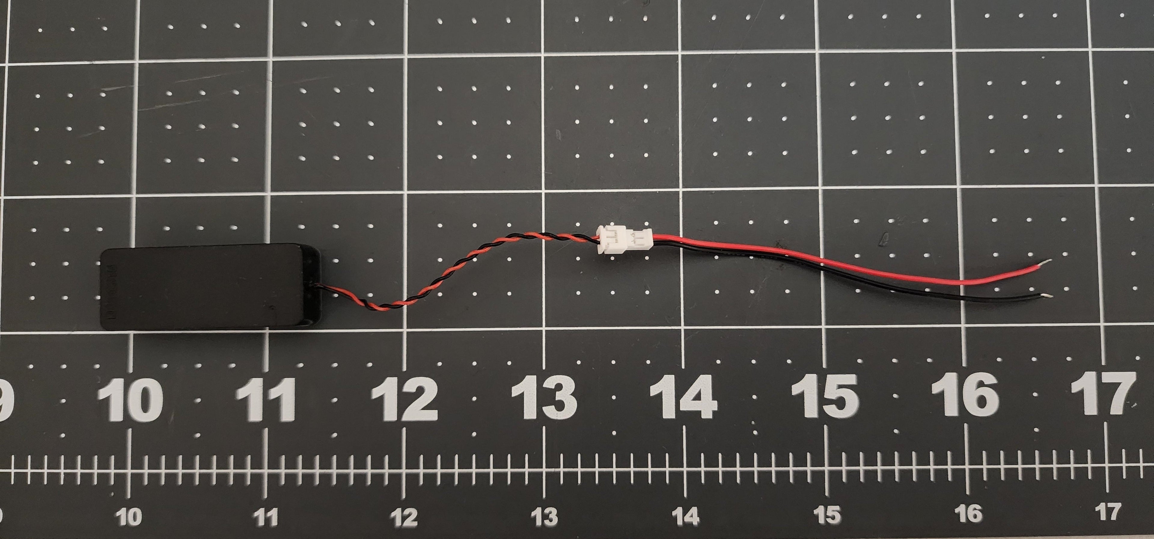 Micro box speaker on a ruled cutting mat showing lead length, JST connector, and included pigtail with bare leads