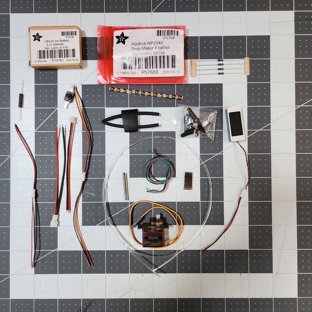 Whistling Birds v2.5 DIY electronics kit contents laid out: Prop-Maker Feather, battery, servo, fiber optic coil, LED strip, speaker, wiring and hardware